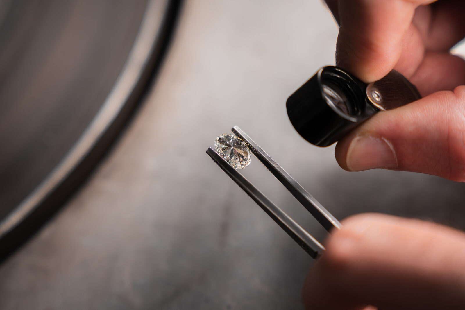 Loose natural diamond held in tweezers beside a loupe at The Diamond Shoppe in Cape Town, ready to be set or proposed with stone-first